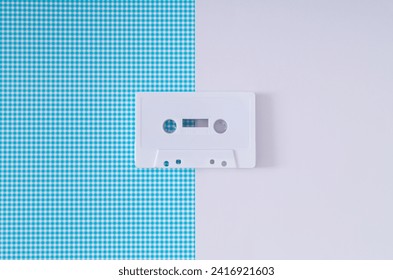 Layout of retro white audio cassette tape on white and blue background. Creative concept of old technology. 80's aesthetic. Vintage audio cassette tape idea. Retro fashion nostalgia. Retro futurism.