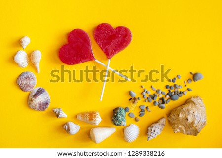 Layout of seashells on a yellow background. Lay flat on holidays and summer vacations.Two candy in the shape of a red heart is a sign of love.
