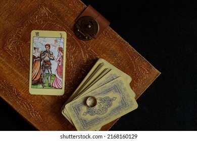 The layout of Tarot cards for relationships. The lovers' lasso and the wedding ring. Flatlay on a black background, and an old book - Shutterstock ID 2168160129