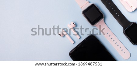 The layout of the watch and the phone on a blue background. Appliances and electronics. Modern gadgets. Phone headphones watch. Business. Wireless headphone. Watch with pedometer.