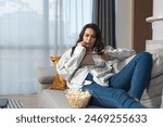 Laziness concept. Young lazy woman lying on the couch watching television in her free time. Weekend activities of business female when she have nothing to do and no will to move from the sofa.