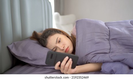 Lazy Asian Young Woman Laying Down On The Bed And Texting In Social Network With A Friends Close Up. 