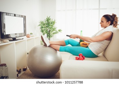 Lazy Beautiful Young Woman In Sport Clothing Sitting Front Of The TV And Doesn't Wont To Exercise.