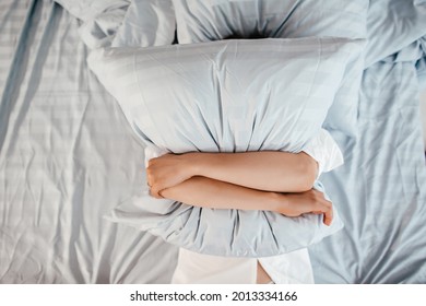 Too lazy to get out of bed, a woman covers her face with a pillow. Early wake up, not getting enough sleep, going work concept. - Shutterstock ID 2013334166