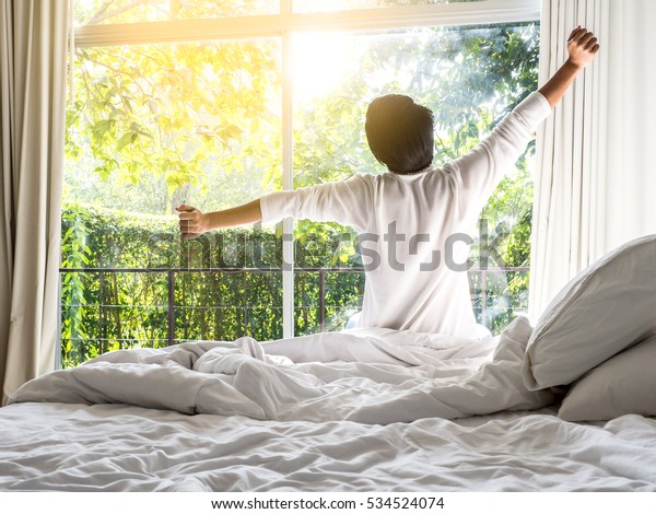 lazy man happy waking up\
in the bed rising hands to window in the morning with fresh feeling\
relax