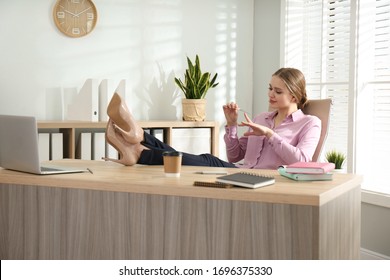 Lazy office worker doing manicure at desk indoors - Powered by Shutterstock