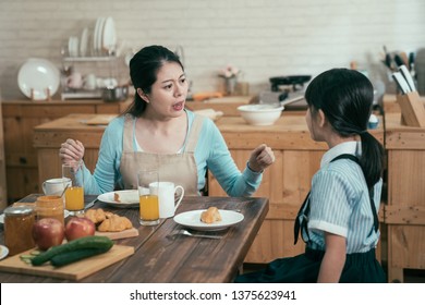 Lazy Sleepy Little Girl Wake Up Late For School Sitting At Kitchen Table With Breakfast At Home. Frowning Angry Mom Loudly Nag At Daughter Bad Habit In Early Morning. Unhappy Asian Mother Worried.