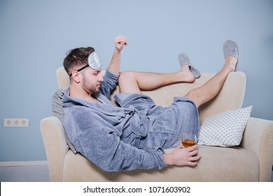 Lazy, Sluggish Man Drinking Whiskey In The Morning, Laying On His Sofa.Young Playboy In Dressing Gown Toasting With Cocktail.Drunk Man Drink Alcohol Lying In Sofa