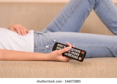Lazy Sunday. Close-up of women lying on the couch and holding a remote control