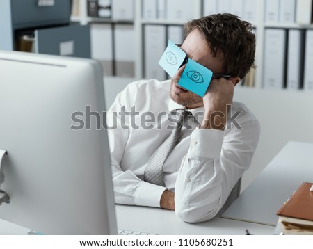 Lazy unproductive office worker wearing funny sticky notes on his glasses and hiding his closed eyes
