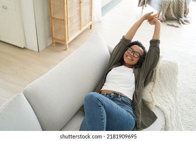 Lazy Weekend Morning Of Teenager. Carefree African American Girl Is Relaxing On Couch And Pillow At Her Apartment. Young Afro Woman Is Stretching And Smiling. Leisure And Rest Concept.