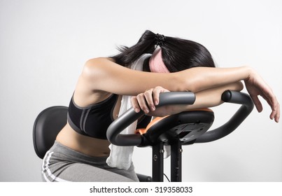 Lazy Woman Sleep On Exercise Bike Over White Background