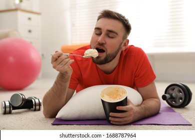 Lazy Young Man Eating Ice Cream Instead Of Training At Home