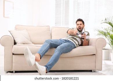 Lazy young man watching TV on sofa at home - Shutterstock ID 1820181221