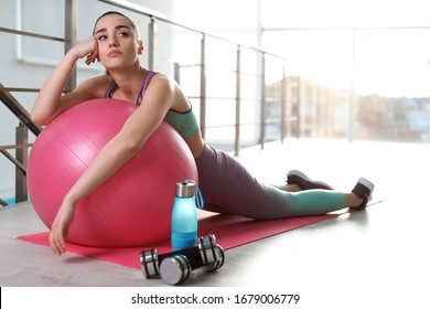 Lazy Young Woman With Exercise Ball On Yoga Mat Indoors