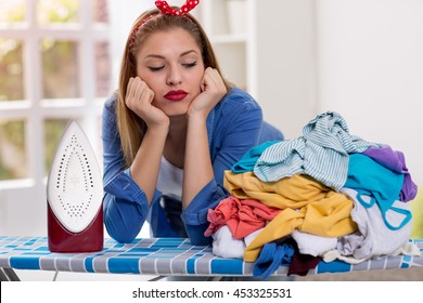 Lazy Young Woman Looks At Laundry On Ironing Board
