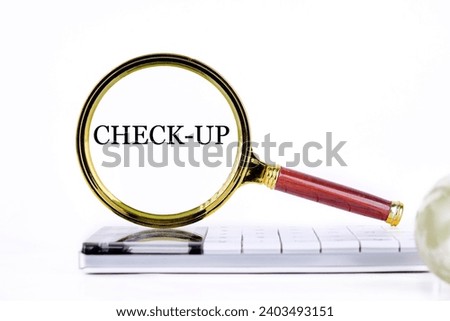 lCHECK-UP ettering through a magnifying glass on a calculator and part of a magic ball in the foreground without focus