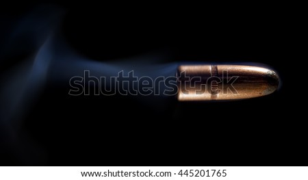 Lead bullet with copper coating on black and smoke behind