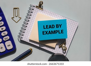 Lead by example message written on ripped torn purple paper on blue background. Conceptual lead by example symbol. Copy space.
