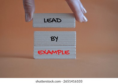 Lead by example symbol. Lead by example written on wooden blocks. Background orange