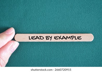Lead by example symbol. Lead by example written on wooden blocks. Background green