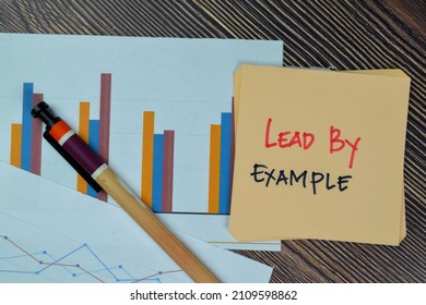 Lead by Example write on sticky notes isolated on Wooden Table.