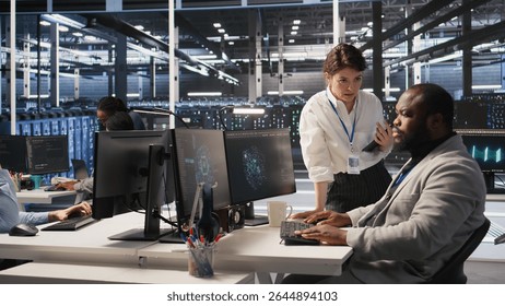 Lead data center admin overseeing IT expert integrating AI in equipment rigs. African american employee under server farm team leader supervision using deep learning for operational tasks, camera A