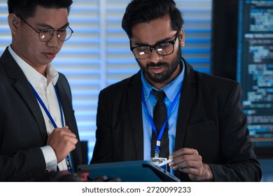 Lead developers analyze system architecture late night using tablet stylus pointing out details colleagues focused code visible screens debugging technical deep dive software build.