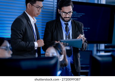 Lead developers analyze system architecture late night using tablet stylus pointing out details colleagues focused code visible screens debugging technical deep dive software build.