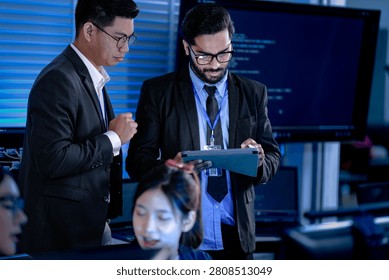 Lead developers analyze system architecture late night using tablet stylus pointing out details colleagues focused code visible screens debugging technical deep dive software build.