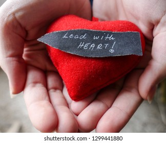 Lead with heart - motivational background, hands with red heart and note 