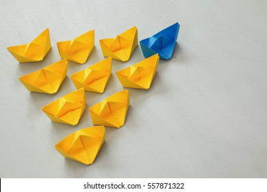 Leadership concept with paper boats on blue wooden background. One leader ship leads other ships. Filtered and toned image - Shutterstock ID 557871322