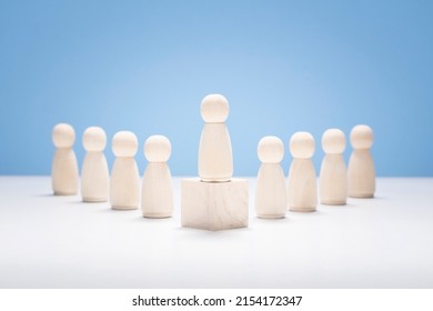 Leadership Concept, Wooden Business Team With One Person Standing Out From The Crowd On Podium