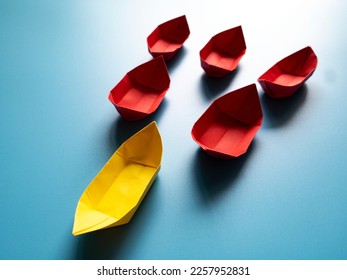 Leadership Concept - Yellow color paper ship origami leading the rest of the red paper ship on blue cover background. Business and copy space. - Shutterstock ID 2257952831