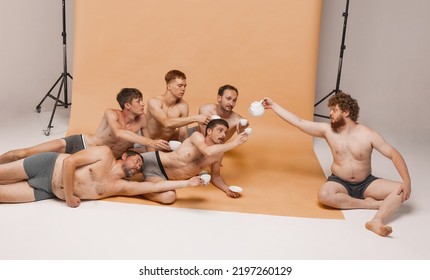 Leadership. Group Of Happy Cheerful Men Of Different Ages And Body Shapes Sitting On Floor And Drinking Tea At Studio Photo Shoot. Feeling Comfortable. Fashion Models Shirtless