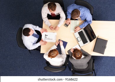 Leadership - Mentoring, Five Business People Meeting - Businesspeople Gathered Around A Table For A Meeting, Brainstorming. Aerial Shot Taken From Directly Above The Table.