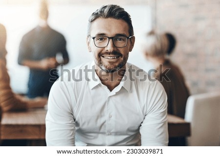 Leadership, portrait of ceo or businessman smile and sitting in office at work with colleagues behind manager. Entrepreneur or business, leader and smiling male person with glasses sit at workplace