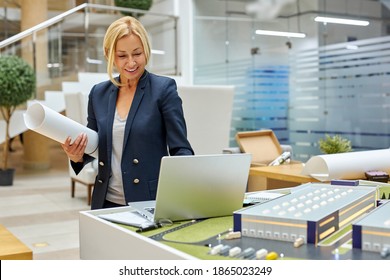 leading architect woman work on laptop while planning process of building, uses small 3d model scale of future building in the office - Powered by Shutterstock