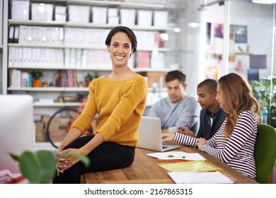 Leading A Dynamic Team Is So Fulfilling. A Young Designer Smiling While Her Team Has A Meeting In The Background.