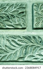 
leaf pattern carved on old stone wall, ancient texture green background, vintage relief.