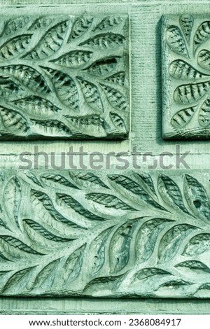 
leaf pattern carved on old stone wall, ancient texture green background, vintage relief.