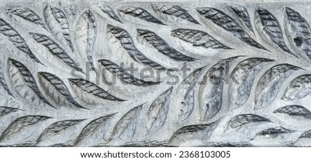 leaf pattern carved on an old stone wall, ancient texture background, vintage relief.