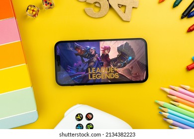 League of Legends (LOL) mobile game app on the smartphone screen. Yellow background with school supplies, children's accessories, video game controller. Rio de Janeiro, RJ, Brazil. February 2022.