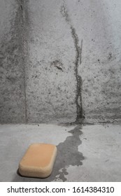 Leaking Crack In A Basement Wall With A Sponge In A Pool Of Water On The Floor