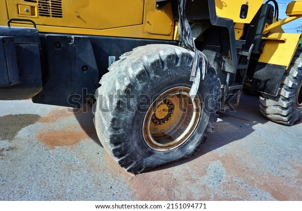 Leaking\
tire of a tractor parking on the floor on the morning before using\
in the day.Maintenance and industries\
concept.