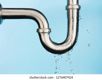 Leaking of water from stainless steel sink pipe on isolated on light blue background