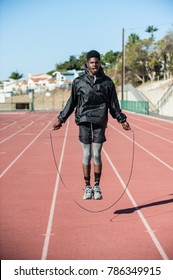 Lean Jamaican Athlete Jumping Over Skip Rope On Track At Stadium. 