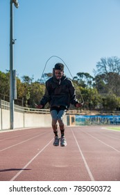 Lean Jamaican Athlete Jumping Rope With Bent Knees On Track At Stadium. 