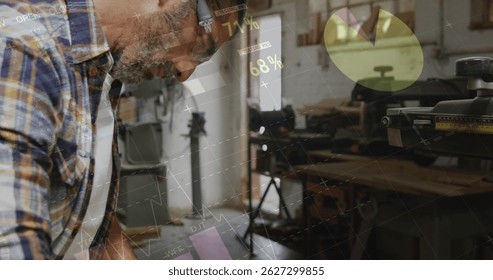 Leaning carpenter manipulating wood pieces at workshop workbench, with earmuffs and table saw. Craftsman, workshop, industrial, tools, woodworking, craftsmanship, hobby