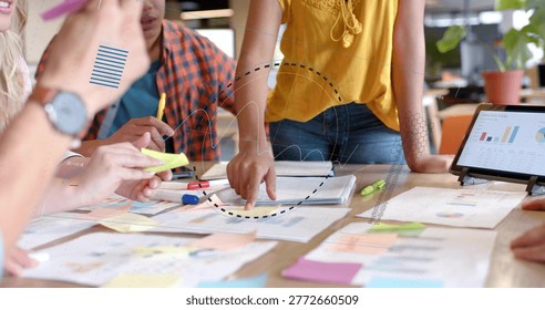 Leaning team of five collaborating at table in office, showing mustard top, tablet and sticky notes. Collaboration, brainstorming, planning, analytics, charts, data, workspace